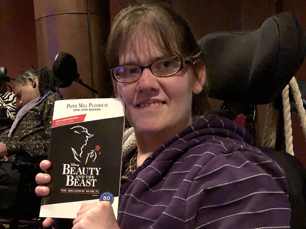 Artist Amanda Kochell holding up her Paper Mill Playhouse program for "Beauty and the Beast".