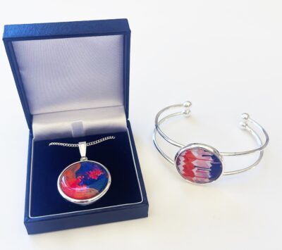 Silver bracelet and necklace set based on paintings by artists Amy Myers and Jasmine Oliver featuring shades of blue, orange, and red.