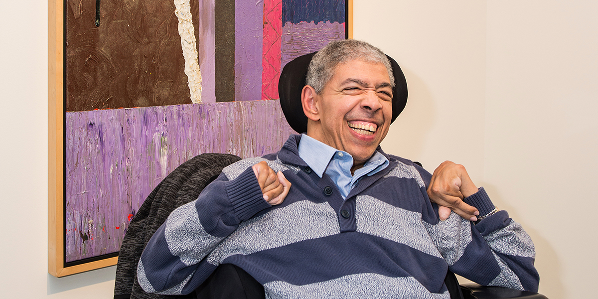 Man in a wheelchair in front of a large abstract acrylic painting