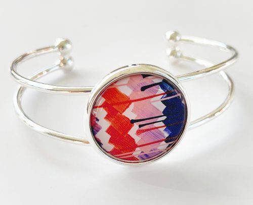Silver bangle bracelet based on a painting by artist Jasmine Oliver titled "Paper" featuring shades of blue, orange, and lavender.