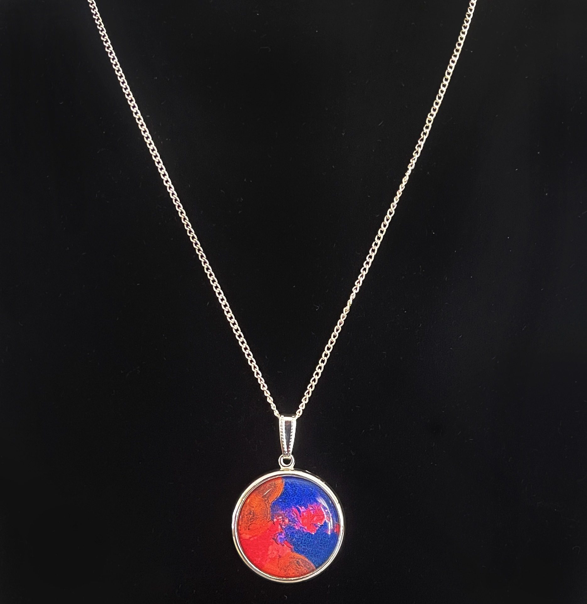 Silver pendant necklace based on a painting by artist Amy Myers titled "No Solutions Yet" featuring shades of blue, orange, and red.