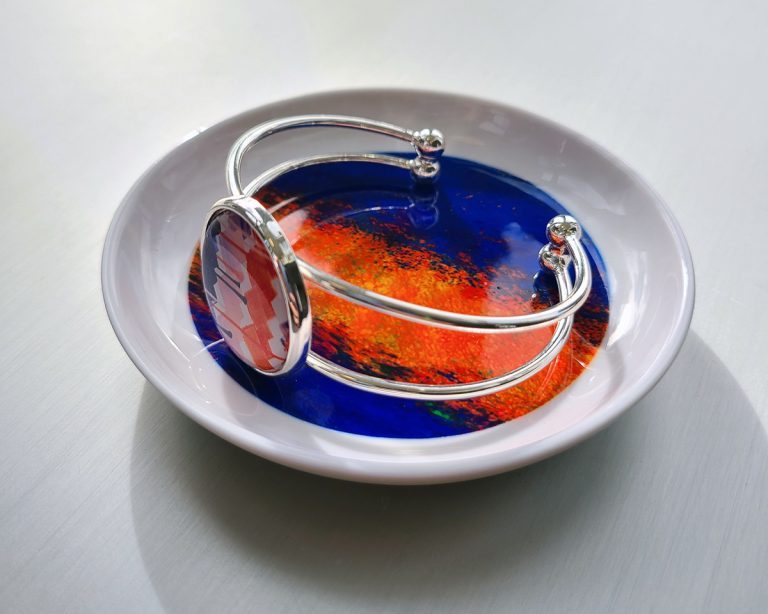 ceramic trinket dish, featuring artwork by Ben Cuison, with a silver bangle sitting on top