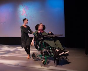 Man in a wheelchair and able-bodied woman dancing together onstage