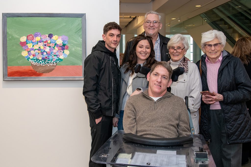 A man in a wheelchair and five able-bodied people in an art gallery