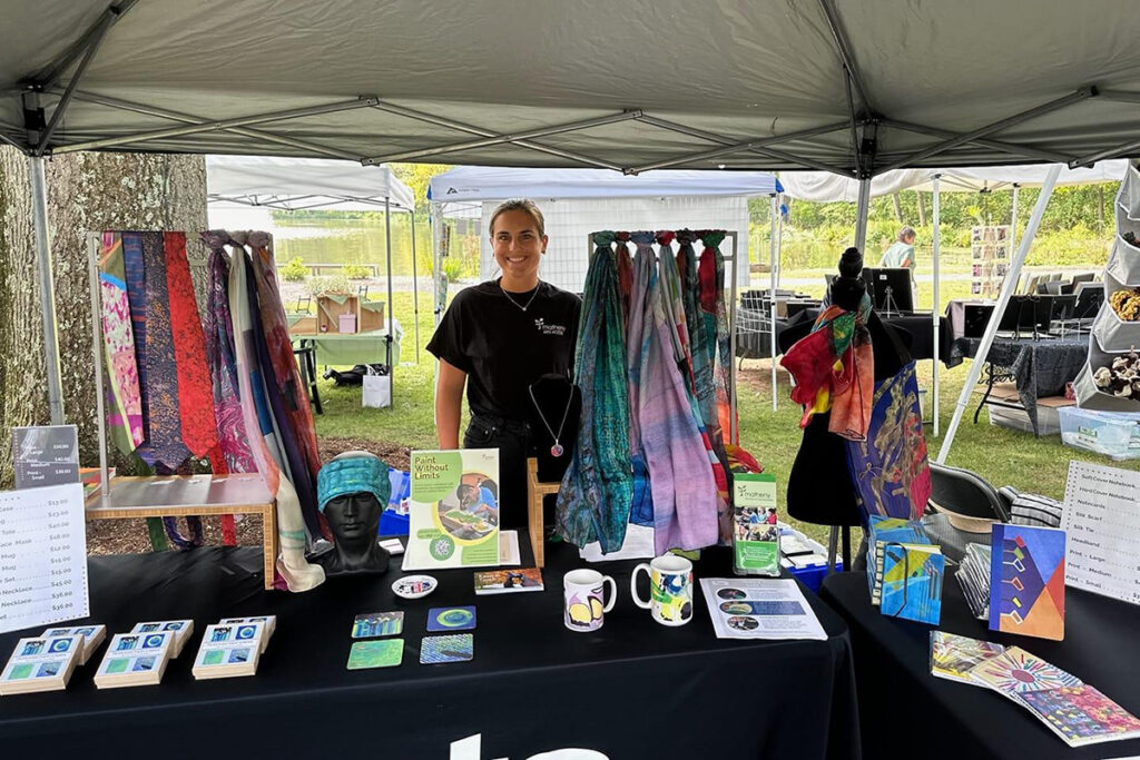 Woman standing behind a table full of items from the Arts Access merchandise collection