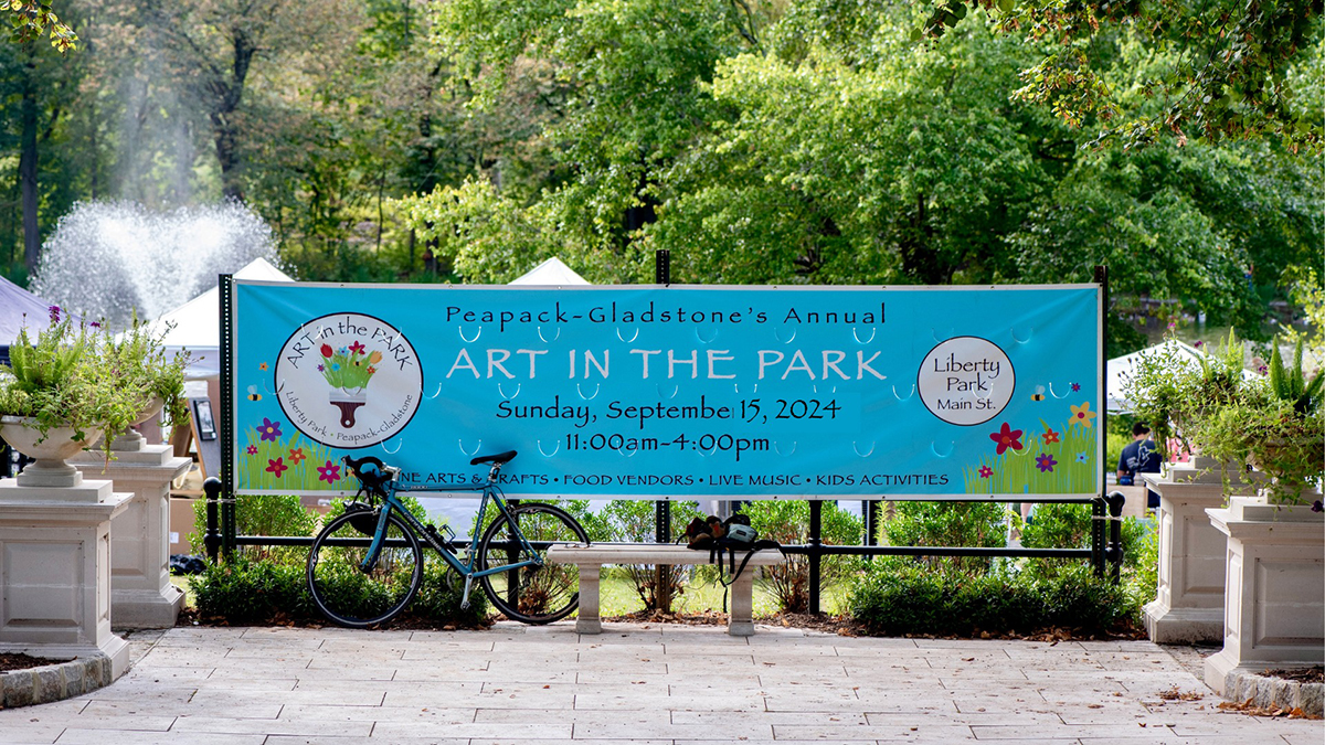 Vinyl banner for Art in the Park 2024 hanging in Liberty Park in Peapack-Gladstone.