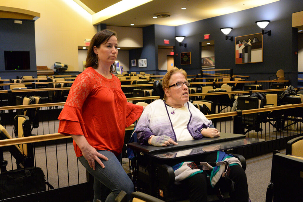 An able-bodied woman and an woman in a wheelchair sitting in an empty theatre.