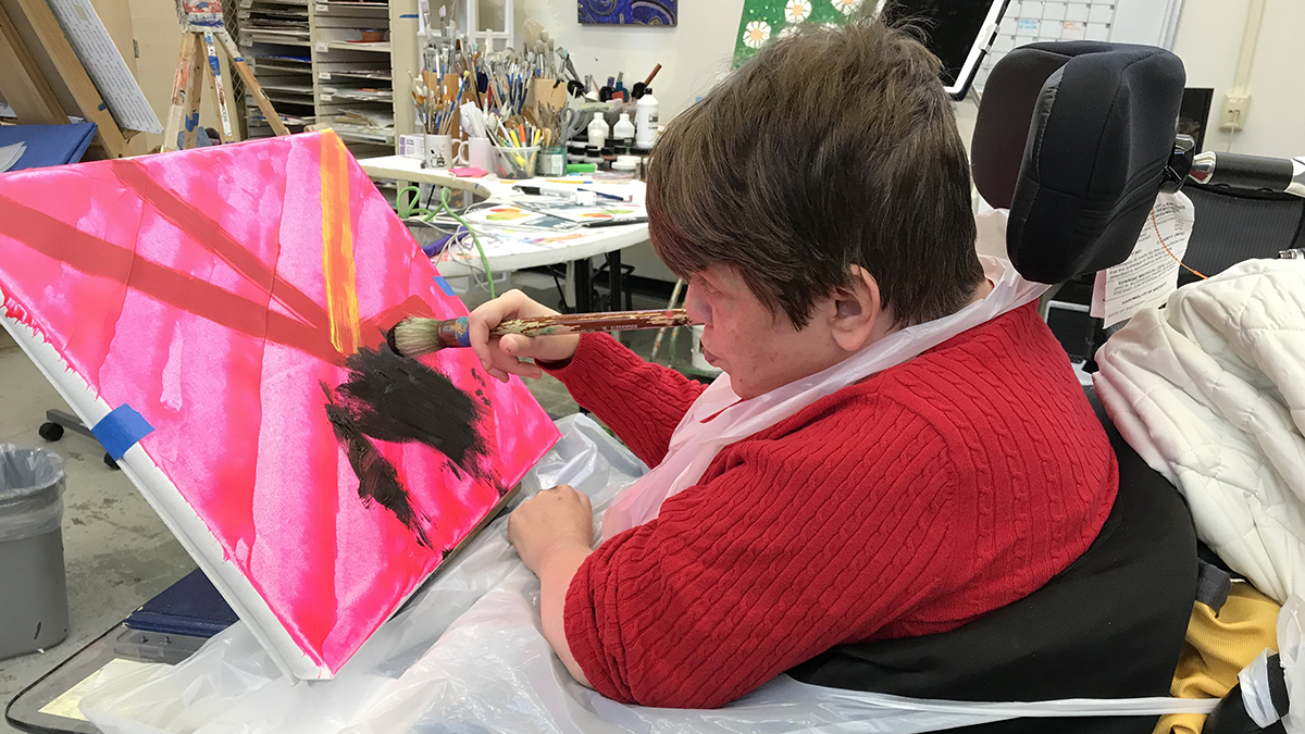 Amy Myers painting on a canvas in the arts studio.