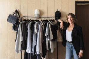 A woman standing next to a clothing rack.
